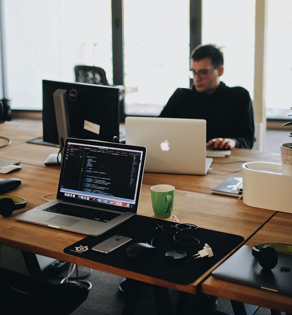 man in black shirt sits behind desk with computers 2102416